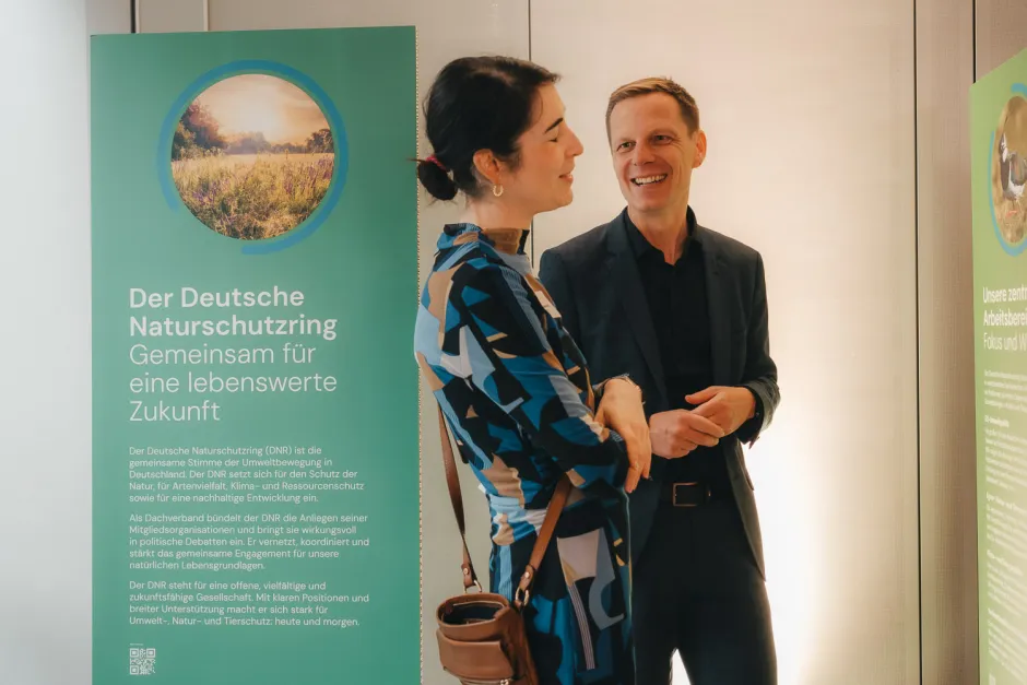 Anna Geuchen (DNR) und DNR-Präsident Kai Niebert im Gespräch inmitten der Ausstellung 75 Jahre DNR